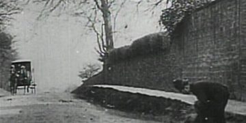 Image is black and white still with a horse and carriage and a police officer