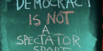 Writing on chalkboard saying Democracy is not a spectator sport