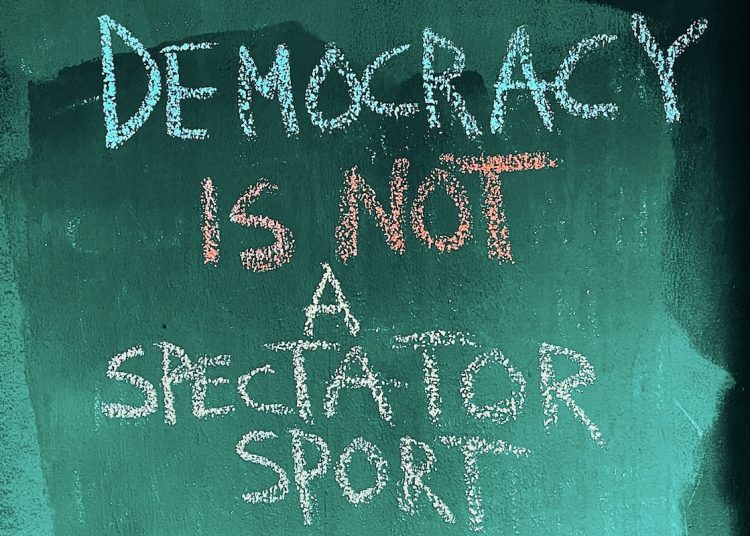 Writing on chalkboard saying Democracy is not a spectator sport