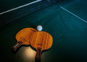 two ping pong bats and a ball on a blue table