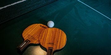 two ping pong bats and a ball on a blue table