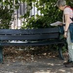 A woman looks at a bench with an inscription on it