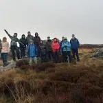 a group of walkers at the top of a hill in late autumn