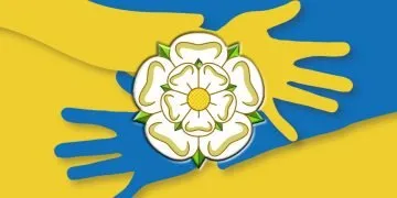 hands crossing over each other in colours of Ukraine flag (blue and yellow) with a white Yorkshire rose on top of the hands
