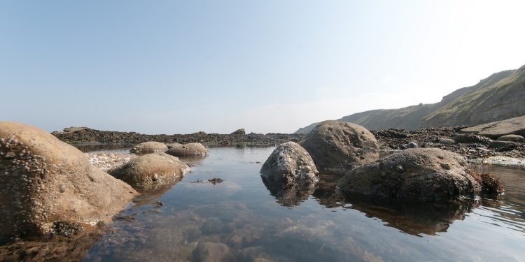 a bay by the sea with some rock pools and large rocks