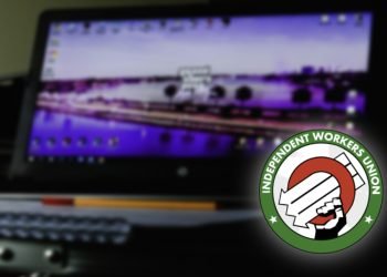 an out of focus image of a computer showing a game on the screen, with a union logo in the bottom corner