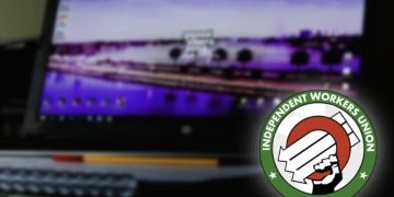 an out of focus image of a computer showing a game on the screen, with a union logo in the bottom corner