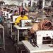rows of Asian women sit at sewing machines in a factory