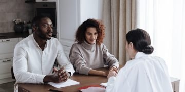 Man and woman discussing documents with a social worker at home.